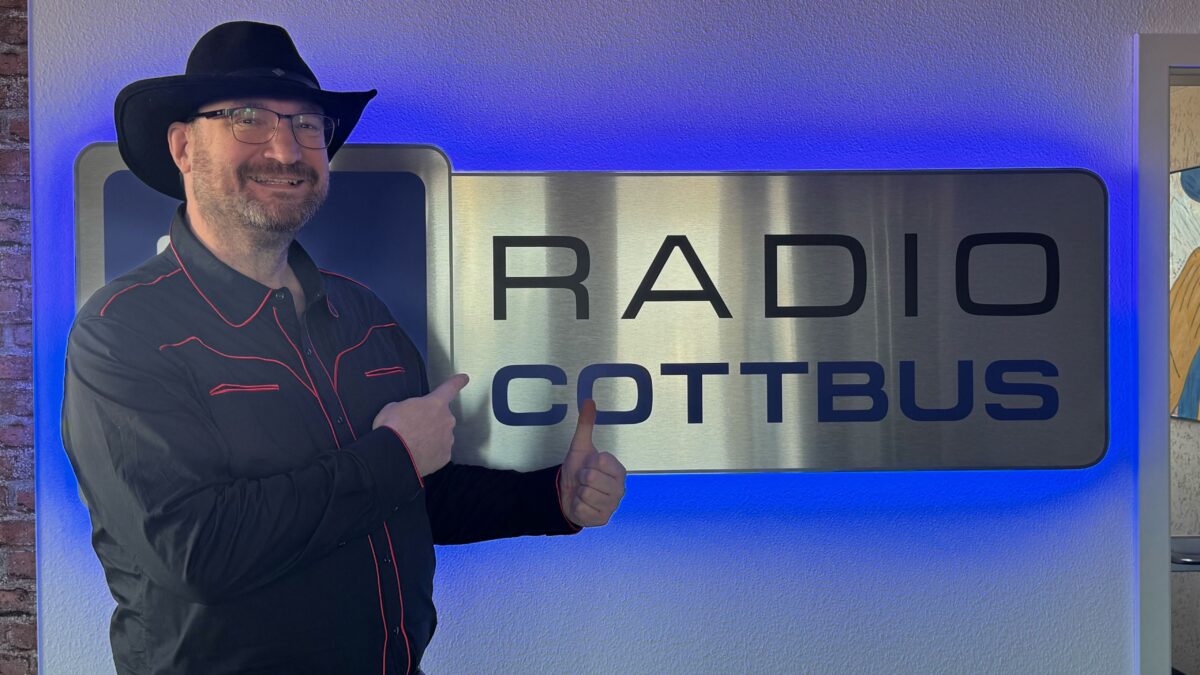 Thorsten Karow vor dem Radio Cottbus Logo